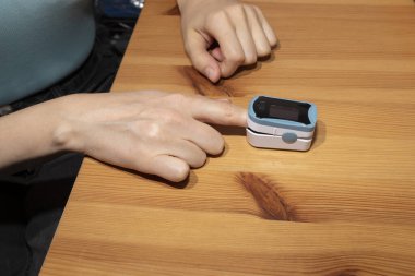 Kişi, kan ve kalp hızındaki oksijen doygunluğunu ölçmek için atım oksimetresi kullanır. Kadın elinin nabız oksimetresi. Sağlık sigortası, Hastalık Önleme. Yatay düzlem. Yüksek kalite fotoğraf