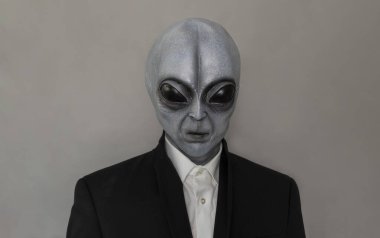 Portrait Of Alien Wearing Suit Gray Background. World UFO Day. Extra Terrestrial Being, Unidentified Flying Objects. Vertical Plane. Grey Humanoid. High quality photo clipart