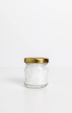 Beyaz masadaki küçük cam kavanozdaki mentollü kristaller. Uzayı kopyala Altın Lid. Doğal Çözüm. Doğal Gıda Seviyesi. Soğutma ve ferahlatıcı etki. Ağrı kesici, Nane Bitkisinin Temel Yağı. Dikey