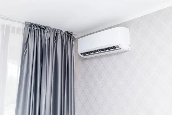 Beyaz Klima, duvarda asılı. Dairenin içindeki duvar kağıtlarıyla süslenmiş. Ev ya da otel. HVC Sistemi. Evde soğuk hava estiren akıllı klima. Yatay olarak. Yüksek kalite.