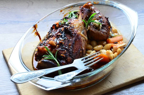 stock image close up view of roast pork knuckle with herbs and beans