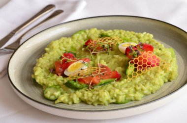 Somon, kuşkonmaz, yumurta ve domatesli yeşil risotto. Restoranda servis ediliyor.