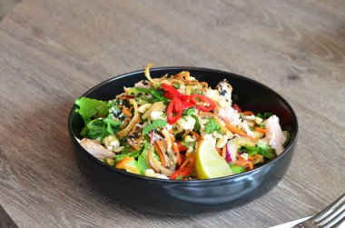 Baharatlı salata, tavuk ve sebzeler ahşap masada kasede.