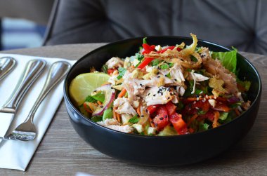 Baharatlı salata, tavuk ve sebzeler ahşap masada kasede.