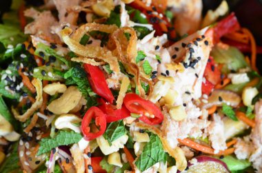 Baharatlı salata, tavuk ve sebzeler ahşap masada kasede.