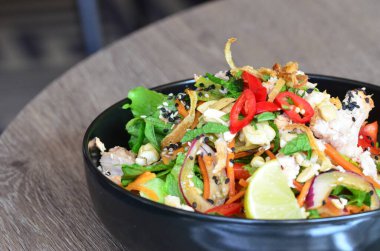 Baharatlı salata, tavuk ve sebzeler ahşap masada kasede.