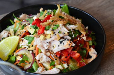 Baharatlı salata, tavuk ve sebzeler ahşap masada kasede.