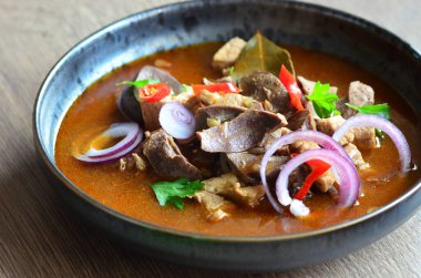 Etten, karaciğerden, omuzdan ve kalpten oluşan gerillalar, geleneksel Çek kasap gerillaları, tahtadan bir masada, yemek arkaplanda, siyah bir tabakta yemek servisi yaptılar.