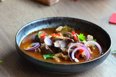 Etten, karaciğerden, omuzdan ve kalpten oluşan gerillalar, geleneksel Çek kasap gerillaları, tahtadan bir masada, yemek arkaplanda, siyah bir tabakta yemek servisi yaptılar.