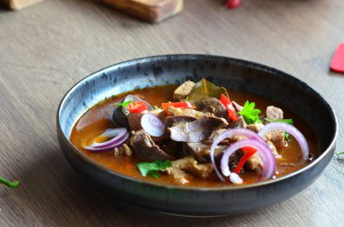 Etten, karaciğerden, omuzdan ve kalpten oluşan gerillalar, geleneksel Çek kasap gerillaları, tahtadan bir masada, yemek arkaplanda, siyah bir tabakta yemek servisi yaptılar.