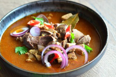 Gulaş, karaciğer, omuz ve kalp parçalı yahni, geleneksel Çek kasabı kebabı, tahta bir masada siyah bir tabakta yemek servisi, yiyecek arka planı, yakın görüş.