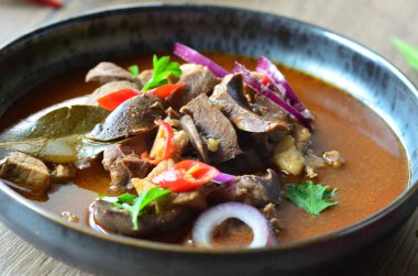 Gulaş, karaciğer, omuz ve kalp parçalı yahni, geleneksel Çek kasabı kebabı, tahta bir masada siyah bir tabakta yemek servisi, yiyecek arka planı, yakın görüş.