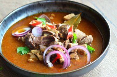 Gulaş, karaciğer, omuz ve kalp parçalı yahni, geleneksel Çek kasabı kebabı, tahta bir masada siyah bir tabakta yemek servisi, yiyecek arka planı, yakın görüş.