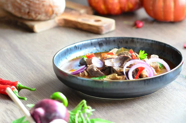 Etten, karaciğerden, omuzdan ve kalpten oluşan gerillalar, geleneksel Çek kasap gerillaları, tahtadan bir masada, yemek arkaplanda, siyah bir tabakta yemek servisi yaptılar.