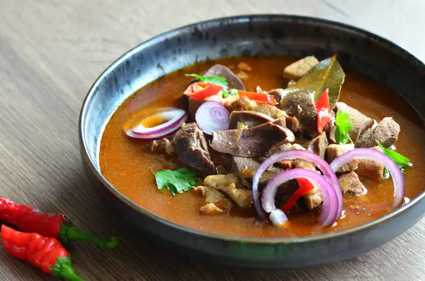 Gulaş, karaciğer, omuz ve kalp parçalı yahni, geleneksel Çek kasabı kebabı, tahta bir masada siyah bir tabakta yemek servisi, yiyecek arka planı, yakın görüş.