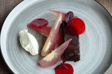 Tatlı geçmişi, restoranda servis edilen yemekler, terbiye edilmiş armut, zencefilli ekmek ve krema, ahşap masada renkli kırmızı yemek.