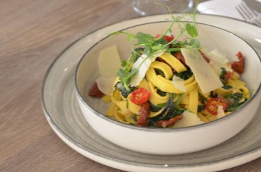 Restorandaki masada makarna, ıspanaklı tagliatelle ve vişneli domates.