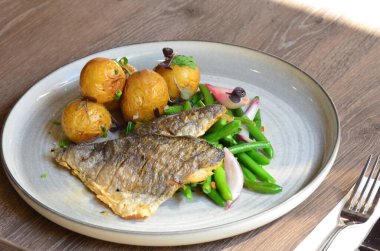 Tabakta patates ve sebzeli kızarmış balık.