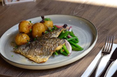 Sebzeli ızgara balık, kızarmış patates, kızarmış patates, yeşil fasulye ve salata..