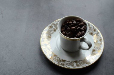 Bir fincan kahve, kahve çekirdeği ve tahta bir masada kaşık.