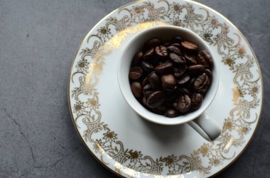 Kahve fincanı ve kahve çekirdekleri beyaz tabakta.