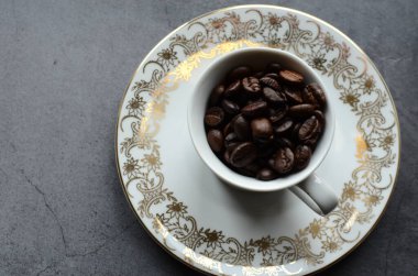 Koyu arkaplanda kahve çekirdeği olan bir fincan kahve.