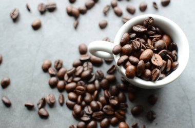 Ahşap masa üzerinde beyaz fincan kahve çekirdekleri