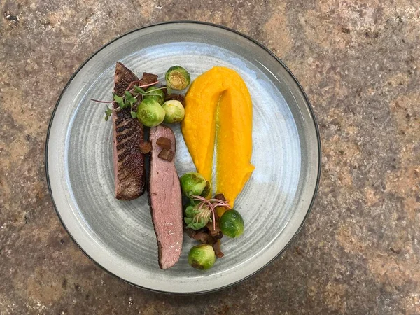 grilled pork and potato, grilled goose breast, pumpkin puree, Brussels sprouts