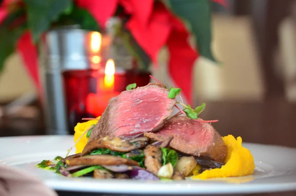 medium roast beef steak, restaurant background, served on a white plate, sliced pink steak with a side dish