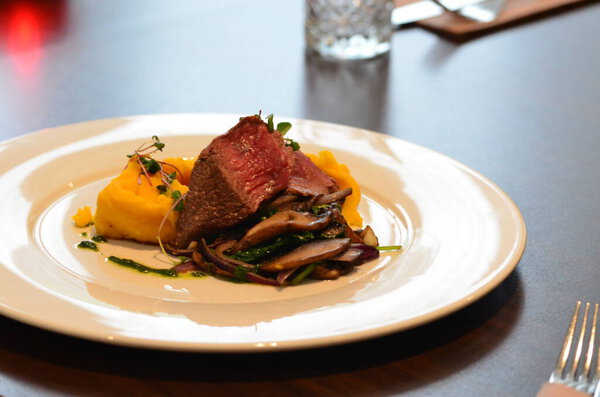 a piece of fried potatoes and beef steak with vegetables.