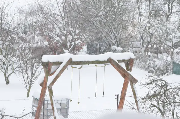 a swing set covered in snow in a yard