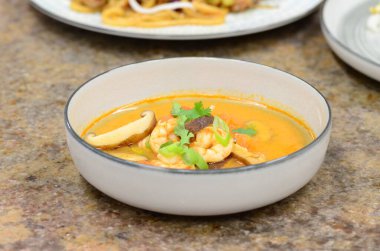 Geleneksel karidesli Asya çorbası, siyah kasede servis edilir.