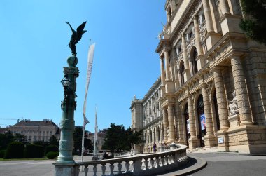 Bir binanın önündeki direkte duran bir kuş heykeli.