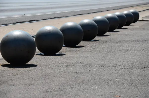 a row of metal balls on the side of a road
