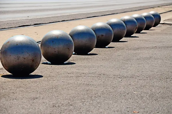 a row of metal balls on the side of a road