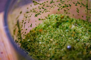 Baharatlı bir kasede yeşil pesto ve mutfakta bir bardak su.