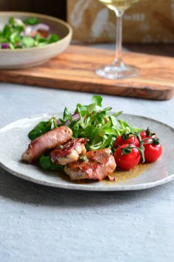 Kırsal bir tabakta servis edilen yemeğin güzel arka planı, İtalyan mutfağı, ızgara dana eti parma jambon ve adaçayı, karışık salata, yakın görüş.,