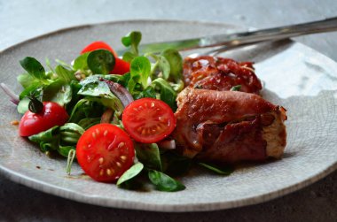 Kırsal bir tabakta servis edilen yemeğin güzel arka planı, İtalyan mutfağı, ızgara dana eti parma jambon ve adaçayı, karışık salata, yakın görüş.,