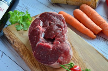 Ahşap arka planda sebzeli çiğ biftek.