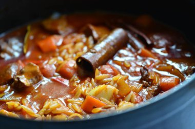 Tahta arka planda tavada et ve sebzeli pilav.