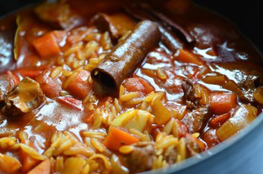 Tahta arka planda tavada et ve sebzeli pilav.