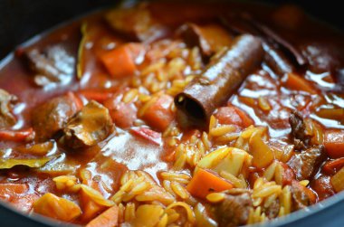 Tahta arka planda tavada et ve sebzeli pilav.