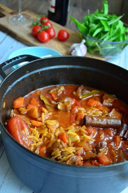 Tahta arka planda tavada et ve sebzeli pilav.