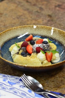 Geleneksel Çek tatlısıyla mavi tabak, haşhaş tohumlu patates gnocchi ve süzme peynir, servis edilen yemeğin arka planı, meyve süslemesi.