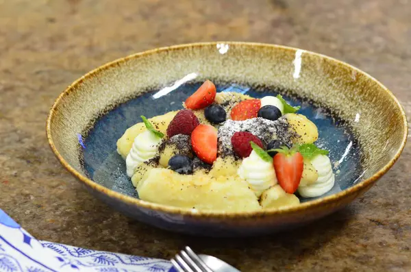 Geleneksel Çek tatlısıyla mavi tabak, haşhaş tohumlu patates gnocchi ve süzme peynir, servis edilen yemeğin arka planı, meyve süslemesi.