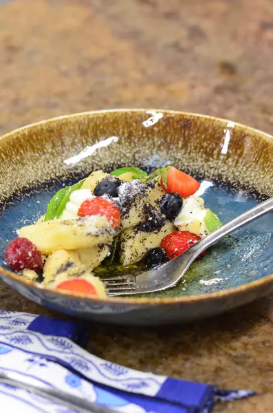 Geleneksel Çek tatlısıyla mavi tabak, haşhaş tohumlu patates gnocchi ve süzme peynir, servis edilen yemeğin arka planı, meyve süslemesi.