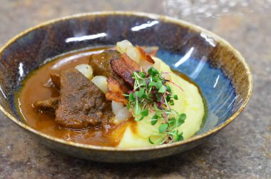 Slow cooked beef cheeks in red wine sauce with mashed potato. Dark background. Top view. clipart