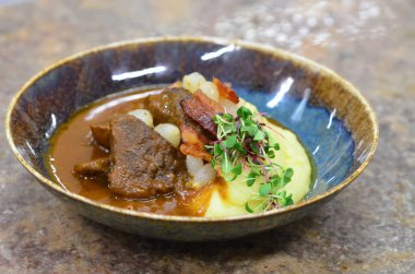 Slow cooked beef cheeks in red wine sauce with mashed potato. Dark background. Top view. clipart