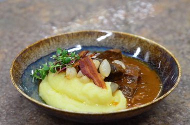 Slow cooked beef cheeks in red wine sauce with mashed potato. Dark background. Top view. clipart