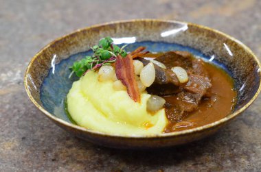 Slow cooked beef cheeks in red wine sauce with mashed potato. Dark background. Top view. clipart